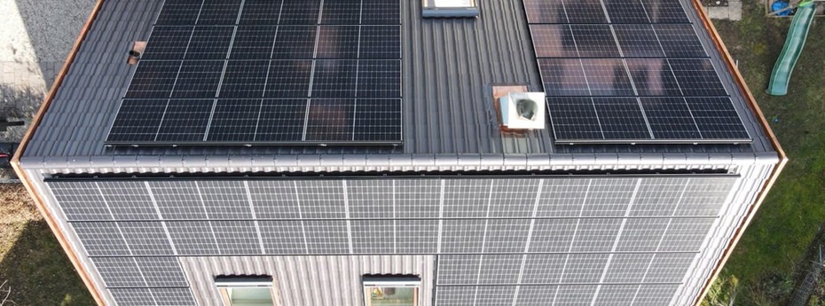 Blick von oben auf ein Einfamilienhaus das an beiden Dachhälften mit Solarpanele installiert hat.